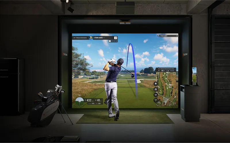 Bay 1 at Swing Spot — a private, fully enclosed simulator room lit with warm gold accents and a glowing TrackMan screen.