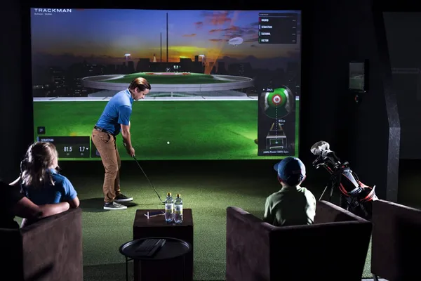 Warm, social evening atmosphere inside a private Swing Spot golf bay.